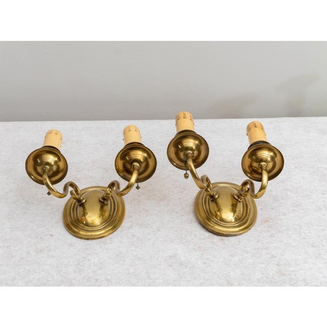 Pair of brass wall sconces, 1950s, Made in Italy. Elegant Pair of gilt brass wall sconces in the style of Louis XVI. They...