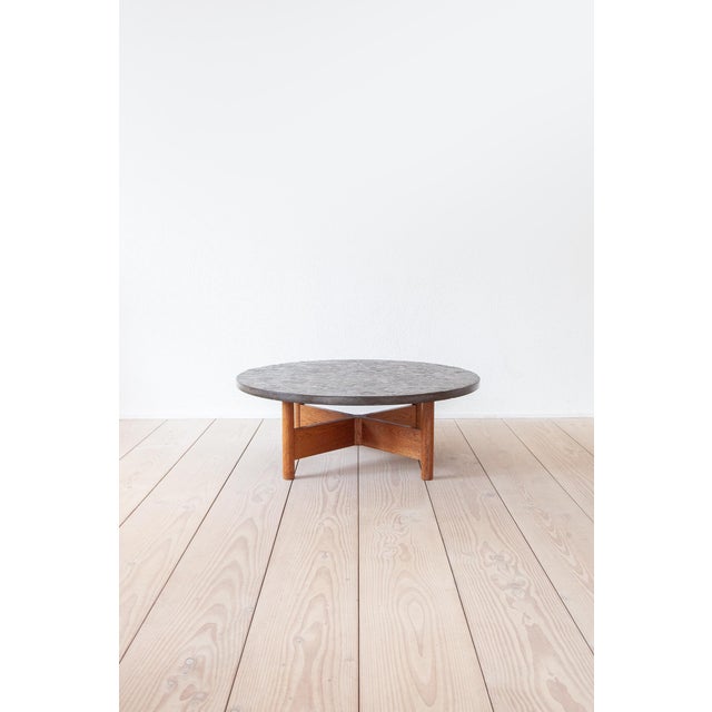 The coffee table features a striking top made of dark slate with beautiful fossil inclusions and an oak base. It most...