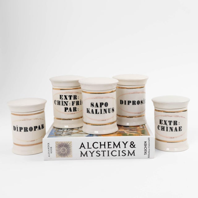 Charming antique-inspired ceramic apothecary jars featuring elegant off-white glazing with delicate gold detailing and...