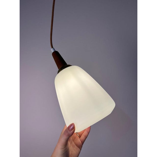 This pendant lamp, crafted from opal glass, teak, and brass, is an exquisite original from denmark, embodying the essence...
