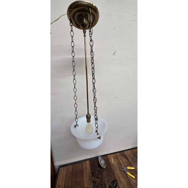 A vintage three-chain frosted glass bowl ceiling light with raised floral decoration and aged metal hardware. The 12-inch...