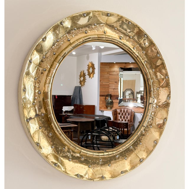 A fine French Mid-Century Modern round wall mirror with a circular frame of hammered brass with chrome rivets -...