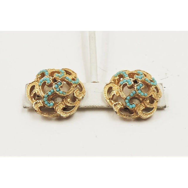 This is part of Chairish’s Costume Jewelry assortment. 1960s goldtone openwork swirl with cabochon faux-turquoise clip...
