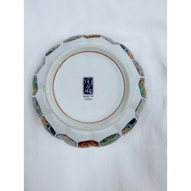 A hand-painted Japanese Arita porcelain bowl with a scalloped rim, featuring the classic Imari palette of cobalt blue,...