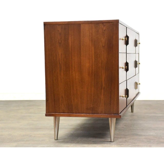 A mid century modern walnut nine drawer dresser with chrome and light brass colored hardware. Professionally refinished....