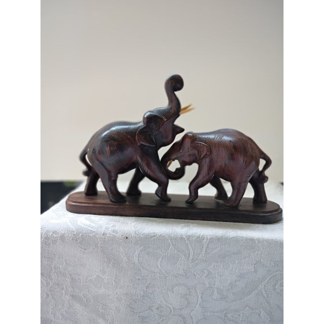 This striking mid-century hand-carved wooden sculpture depicts two stylized fighting elephants locked in motion on an...