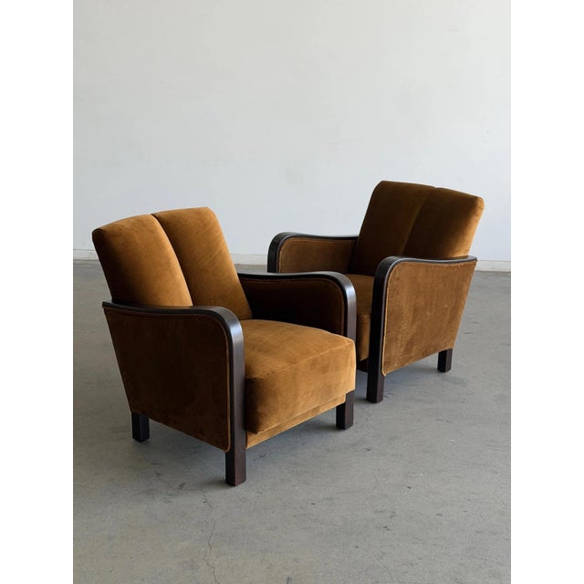 W27 D35.25 H31.5 SW19 SD22.75 SH17.5 AH23.5 A striking pair of Art Deco lounge chairs featuring sculptural dark wood...