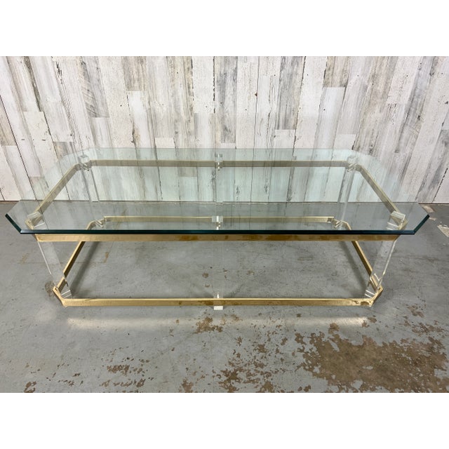Golden glow of the polished brass stretcher and top rim offset the six lucite legs with a floating beveled glass top with...