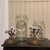 A set of 2 graduated canisters of clear glass with gold metal lids featuring a Reticulated edge and topped with white...
