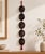 A striking vintage Korean wall hanging composed of five miniature carved wooden character masks suspended vertically on...
