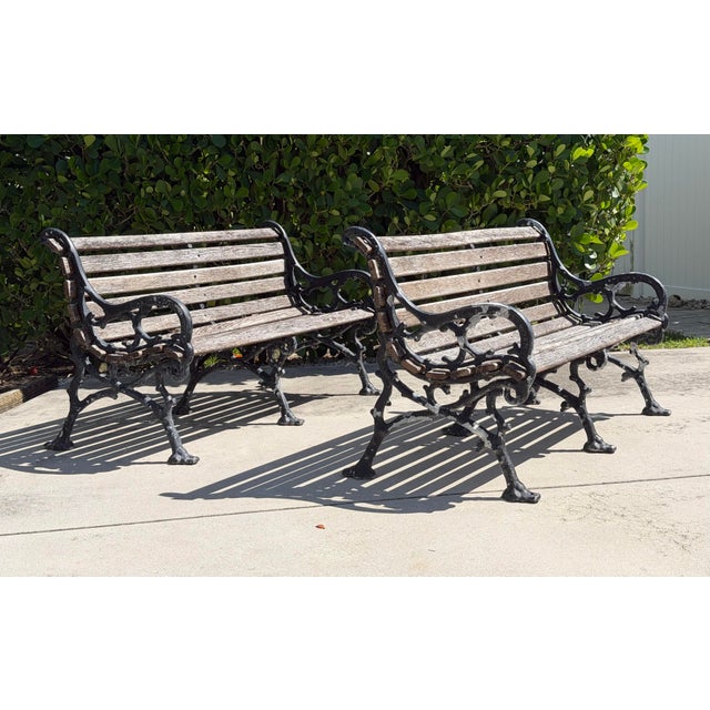A matched pair of vintage garden benches with ornate cast-aluminum frames and hardwood slats. The substantial scrolling...
