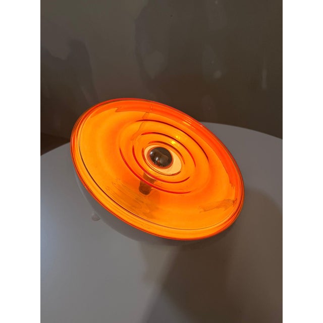 Vintage Space Age table lamp from France, 1970s, with an orange glass dome and white metal base. The round, bowl-like...