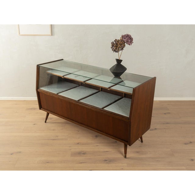 A wonderful shop counter from the 1950s. Its body is made of walnut veneer, with eight drop-leaf doors, eight drawers with...