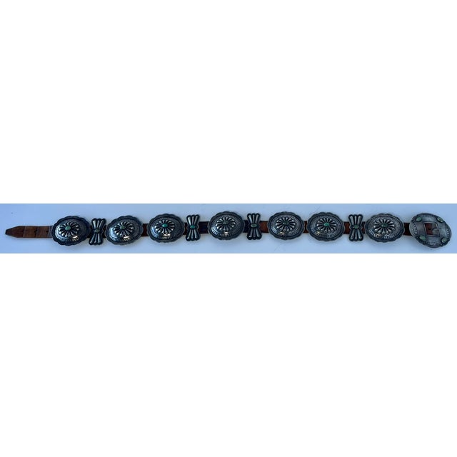 This fantastic belt has 11 heavy hand-stamped silver conchos with scalloped edges and a central turquoise cabochon in...