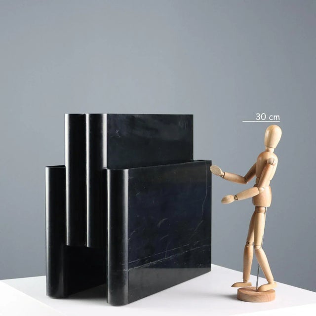 Four-compartment magazine rack in black plastic. This piece is attributed to the mentioned designer/maker. It has no...