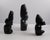 A striking set of three hand-carved black obsidian figural sculptures, each showcasing bold, stylized forms with a smooth,...