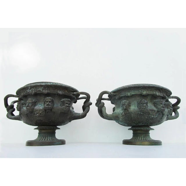This pair of bronze Antique Warwick vases or planters was produced in Italy in the early 19th century. The top has a...