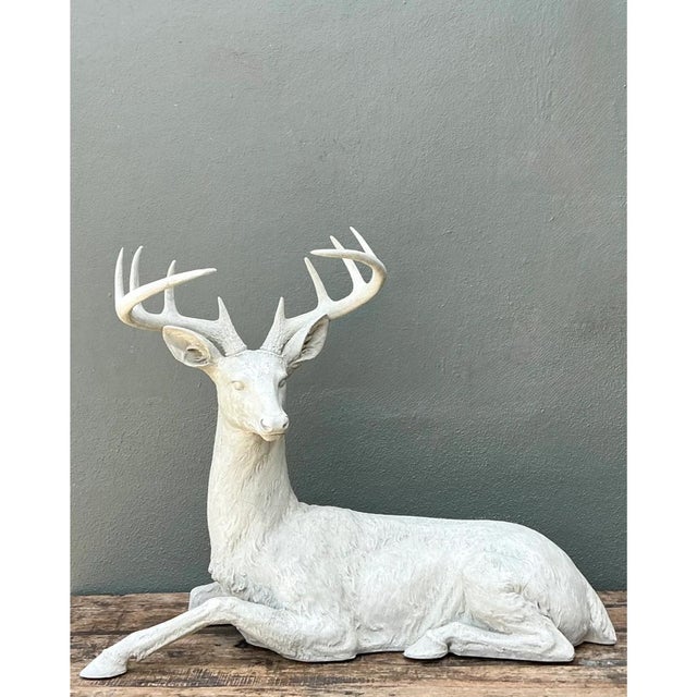 This vintage life-size sculpture captures a mature stag in a calm, recumbent pose, its body settled low to the ground...