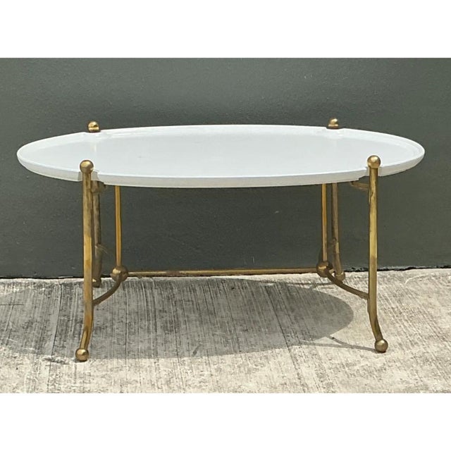 Distinguished by its graceful architectural lines, this vintage oval coffee table features a smooth white tray-style top...