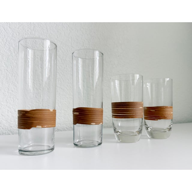 Set of four Mid-Century Modern, Carl Auböck style clear glass and rattan wrapped cocktail glasses. Includes a pair of...
