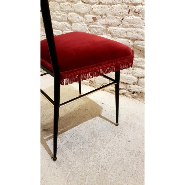This large vintage wrought iron chair features brass details and velvet upholstery. It was made in France in the 1950s.