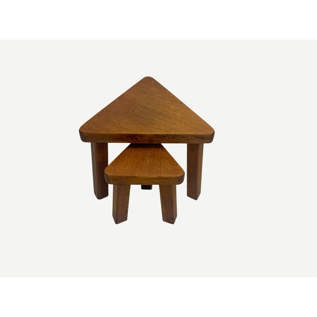 A set of 2 triangular shaped nesting tables in a warm color solid oak, made with craftsmanship with a thick top and legs,...