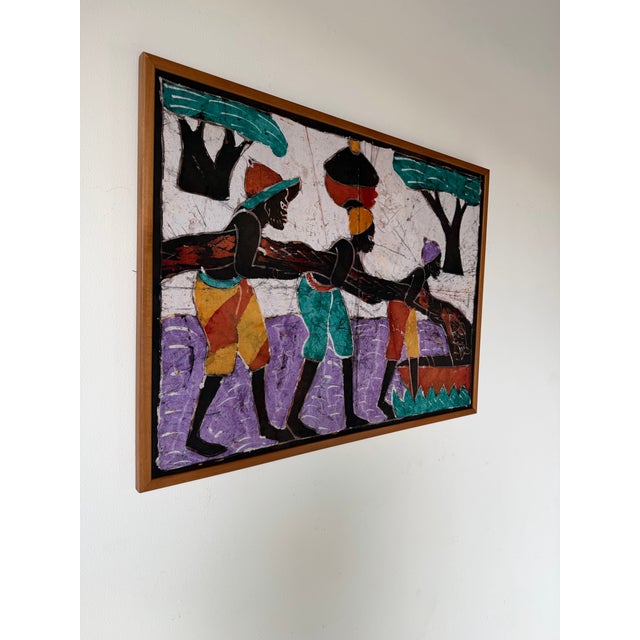 A striking vintage African batik wax-resist textile wall hanging showcasing a traditional village scene with workers...