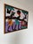 A striking vintage African batik wax-resist textile wall hanging showcasing a traditional village scene with workers...
