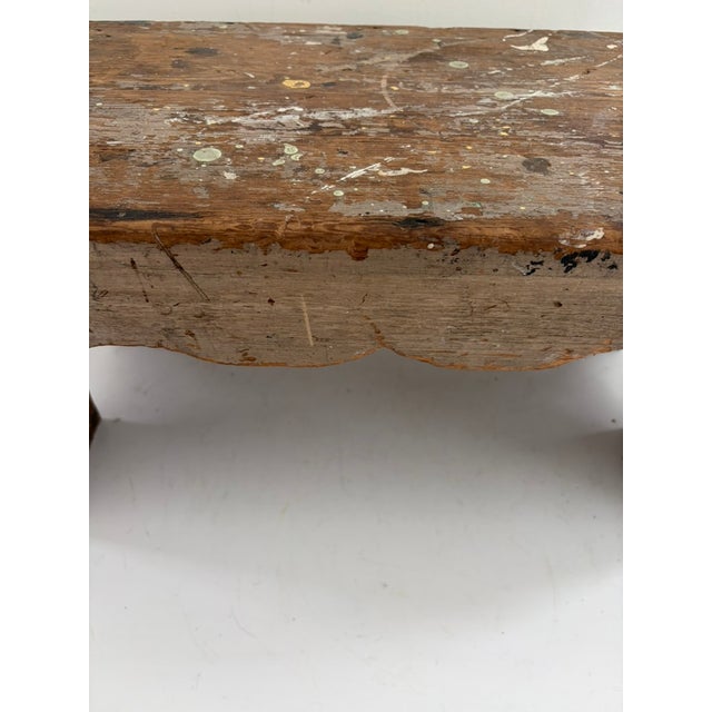 Vintage painter’s bench constructed from solid wood with a rectangular plank top and splayed block legs. The bench shows...