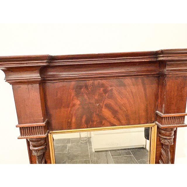 An antique trumeau mirror with an intricate, mahogany frame. Historically designed to be placed between windows or above a...