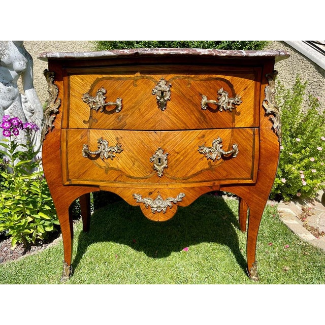 Louis XV commode in marquetry decorated with bronze in good condition. It opens with two drawers and has a marble on top....