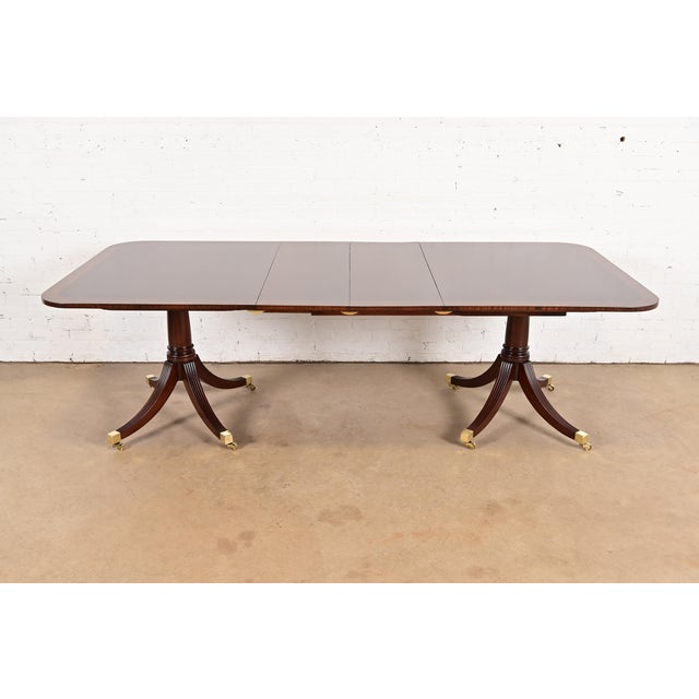 An exceptional Georgian or Regency style double pedestal extension dining table In the manner of Baker Furniture USA,...