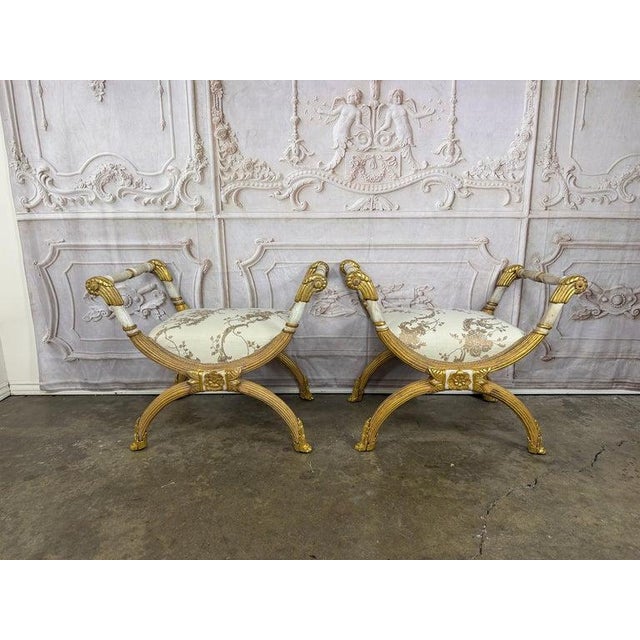 A magnificent pair of Italian Neoclassical curule stools, embodying timeless grandeur and Hollywood Regency glamour. This...