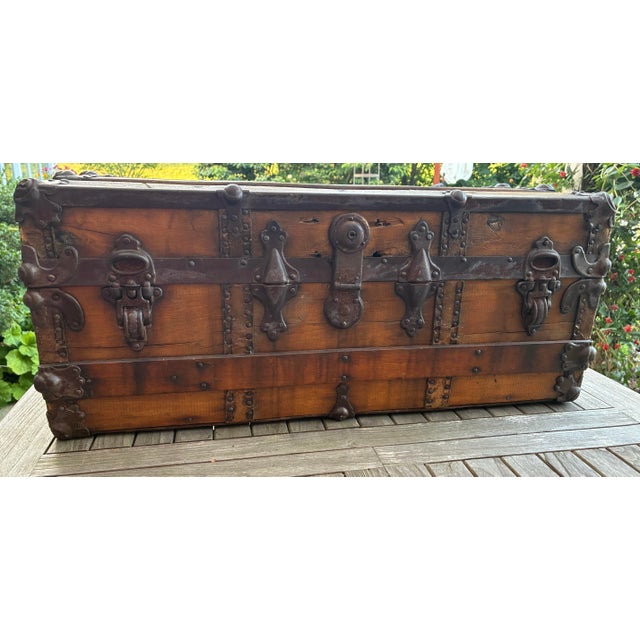 A handsome late 19th-century American flat-top travel trunk featuring warm, aged wood accented by original hand-riveted...