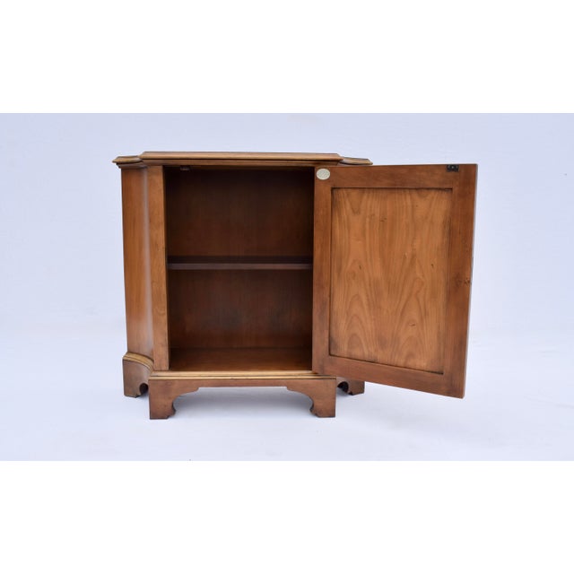 A console cabinet or commode by Baker Furniture, circa 1960s of French cherry wood with a single raised panel door and one...