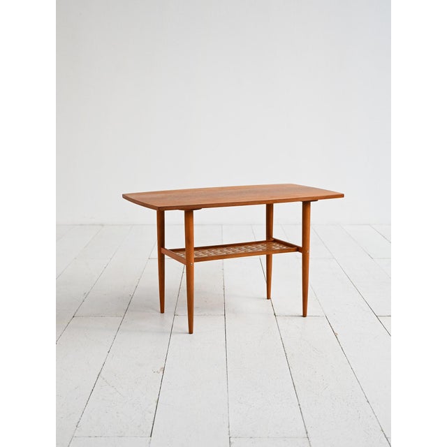 Made by Alberts Tibro (Sweden), 1960s. Teak coffee table with a contoured top, tapered legs, and a lower shelf made of...