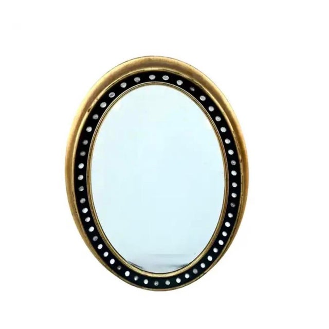 Irish Regency Style Oval Mirror features a refined Ebonized Wood Frame accented with Parcel Gilding and meticulously set...
