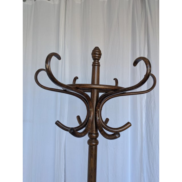 Vintage bentwood coat stand made from dark brown curved wood. The design features elegantly curved hooks, decorative...