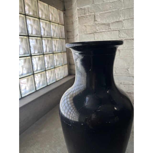 This dramatic black floor vase cuts a striking figure. The smooth, curved body and tapered neck offer a touch of 80s...
