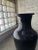 This dramatic black floor vase cuts a striking figure. The smooth, curved body and tapered neck offer a touch of 80s...