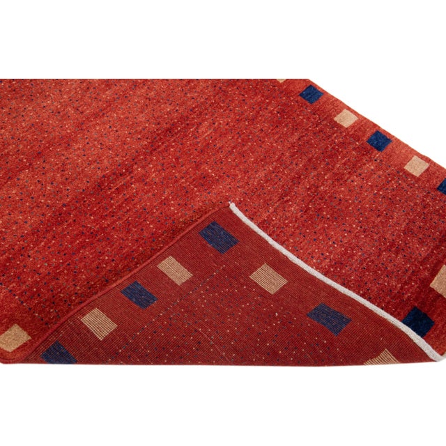 Beautiful modern Gabbeh hand-knotted wool rug with a red field. This Persian rug has beige and blue accents in a...