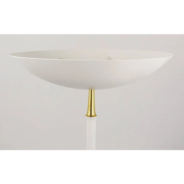A beautiful white Italian floor lamp in the style of Arteluce. Has a white wooden stem, a perforated uplight bowl...
