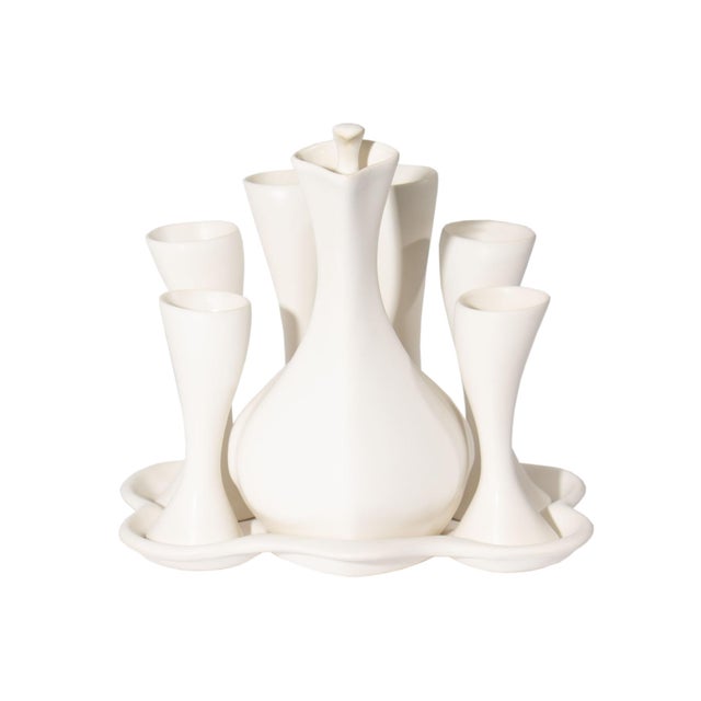 A white porcelain sake set designed by the American artist Peter Saenger. This set features smooth curving organic shaped...