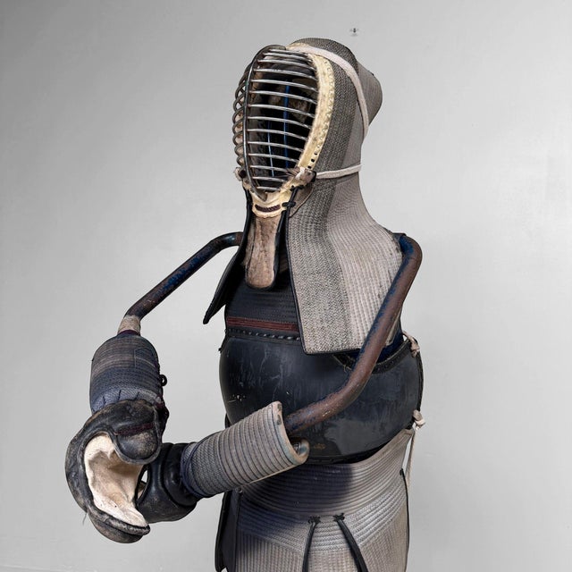 Decorative vintage Japanese kendo equipment, or bōgu, presented on an adjustable metal display stand, presumably dating...