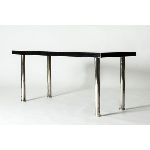 Elegant console table by Axel Einar Hjorth, in a sleek, functionalist design. Wooden table top lacquered black, cylinder...