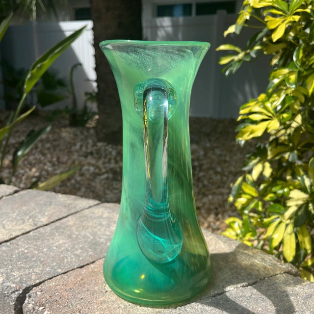Eye catching green swirls mixed in with clear glass and accented with green at base and rim. It’s a little tricky to see...