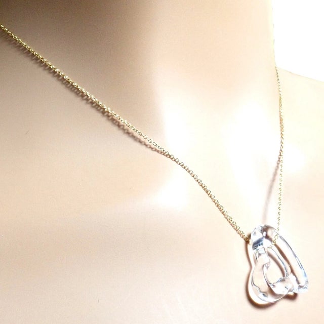 This Tiffany & Co. necklace by Elsa Peretti features a large rock crystal open heart pendant and is suspended from an 18k...