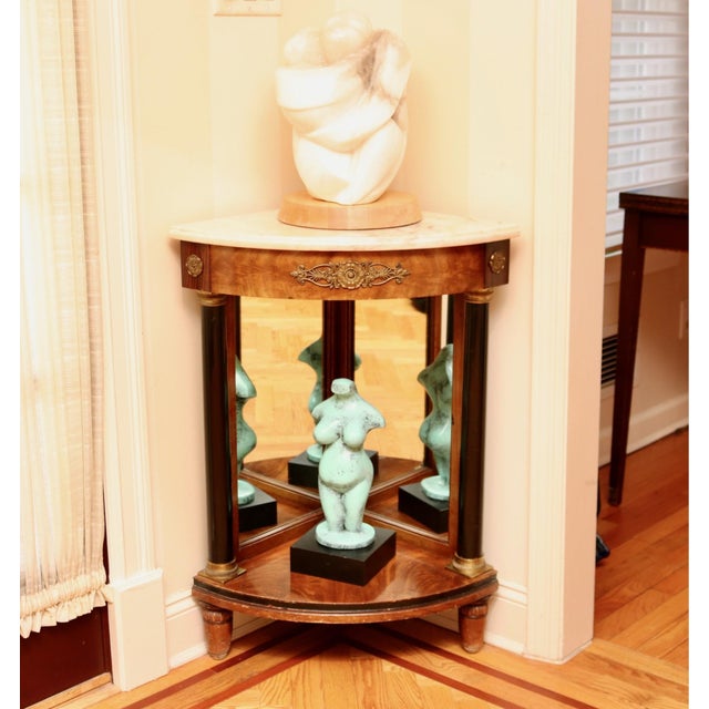 An antique corner table with a marble top, mirrored panels, columned base, lower shelf and bronze ormolu mounts. Product...