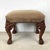 This striking footstool features dramatic carved grotesque mask knees, a hallmark detail drawn from the Gothic Revival and...