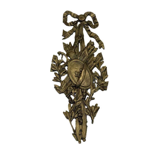 Elegant Louis XVI–style wall ornament crafted in gilt-tone metal, featuring a sculptural ribbon-and-bow crest above a...